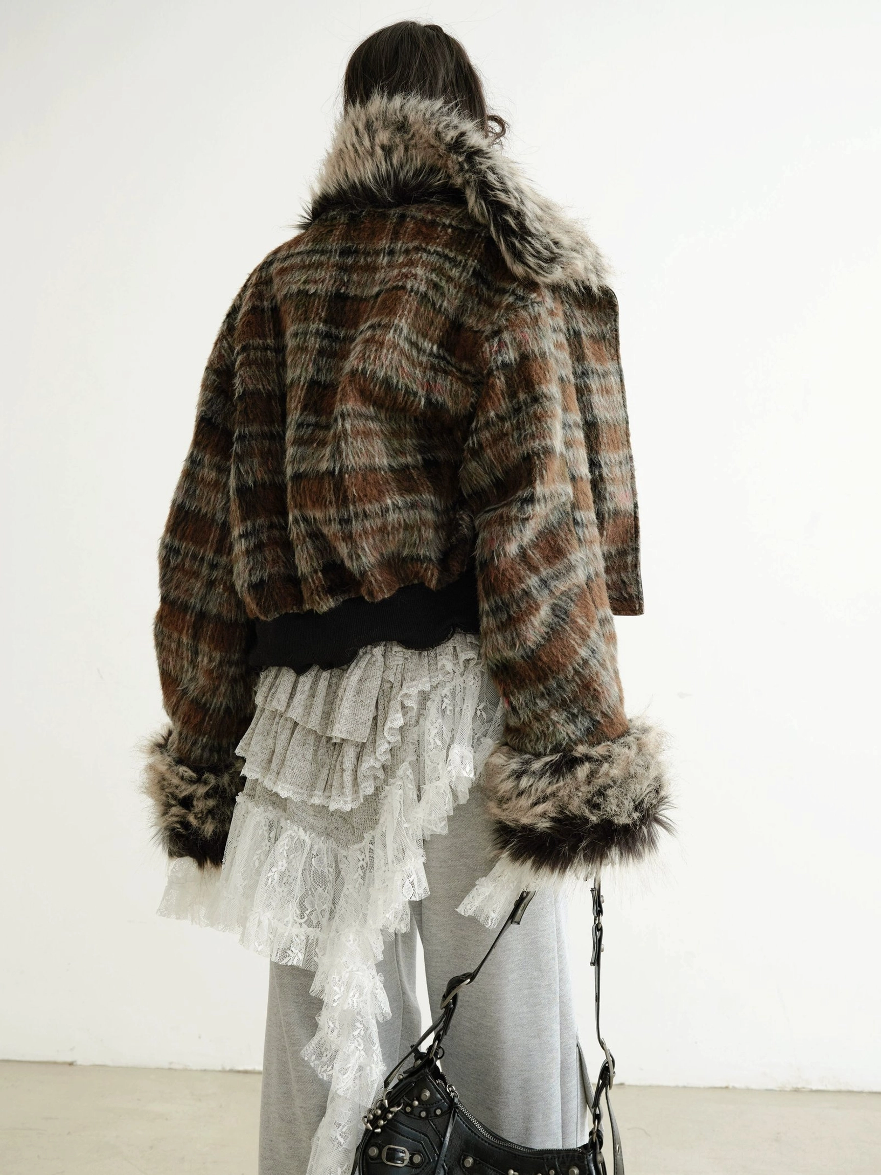 Back view of a dark brown cropped faux fur jacket showing the plush collar cuffs hem and relaxed bomber-inspired silhouette