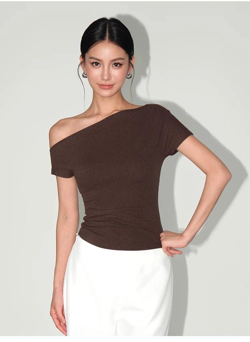 Dark brown fitted asymmetric one-shoulder streetwear tee styled with white bottoms in a studio portrait
