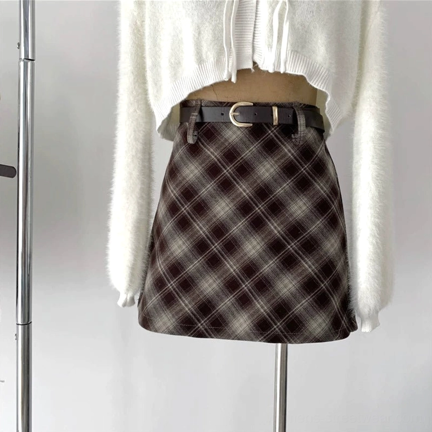 Close-up view of a dark brown and gray plaid high-waisted wool skirt styled with a black leather belt on a studio mannequin