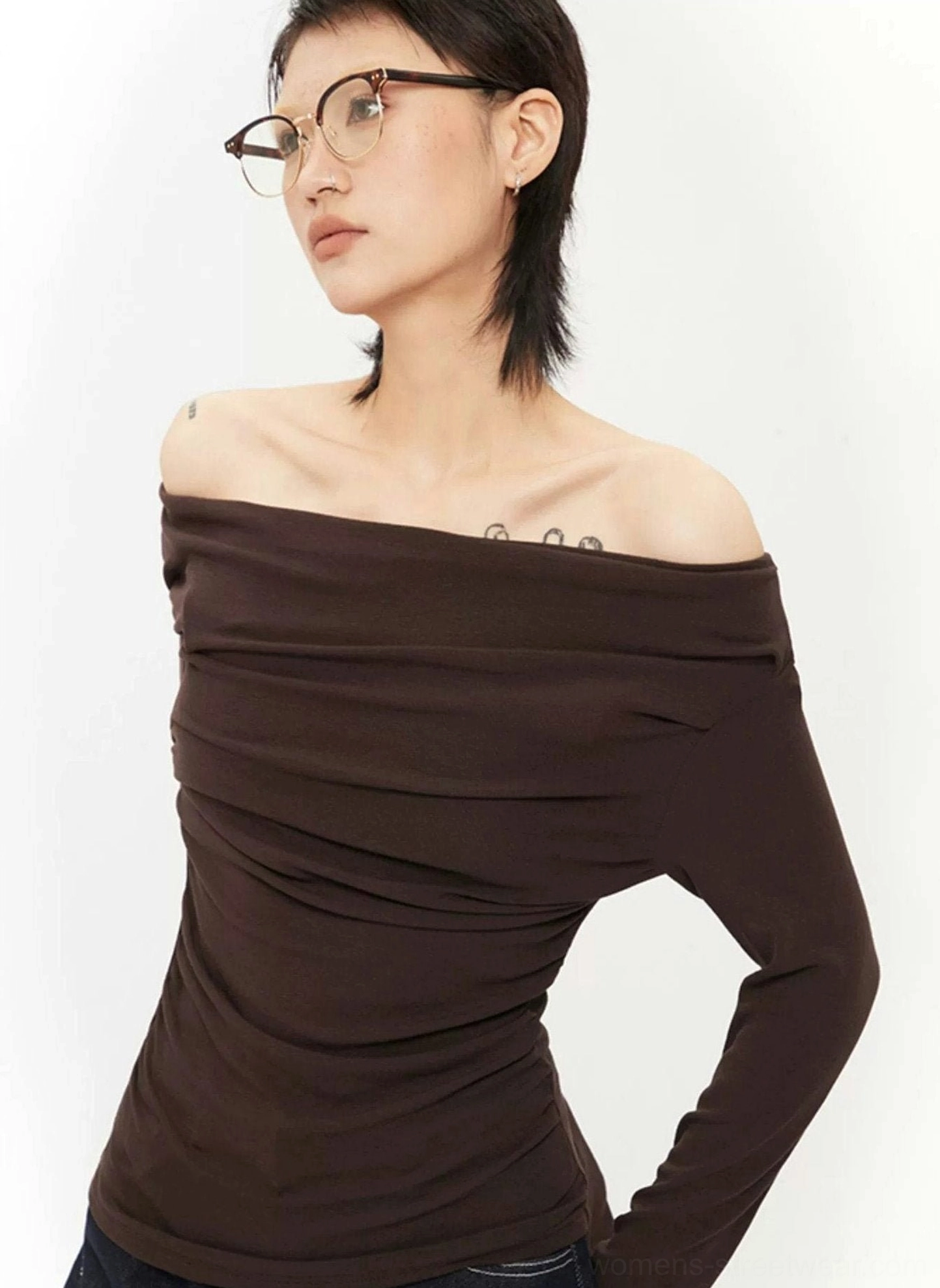 Close-up side view of dark brown off-shoulder ruched knit top showing one bare shoulder, draped neckline, and long sleeve