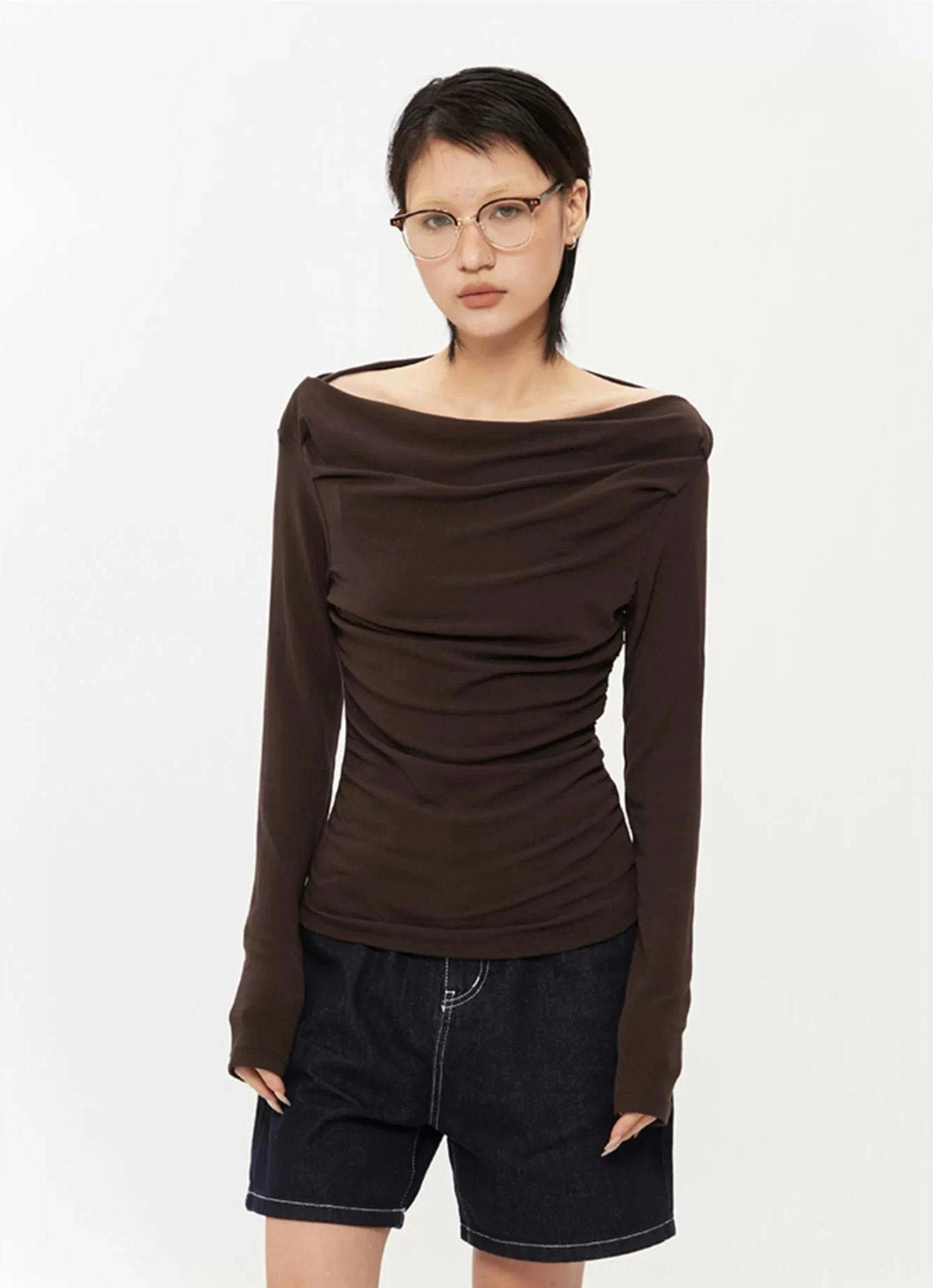 Dark brown off-shoulder ruched long-sleeve top with draped neckline and fitted Korean streetwear silhouette styled with dark denim shorts