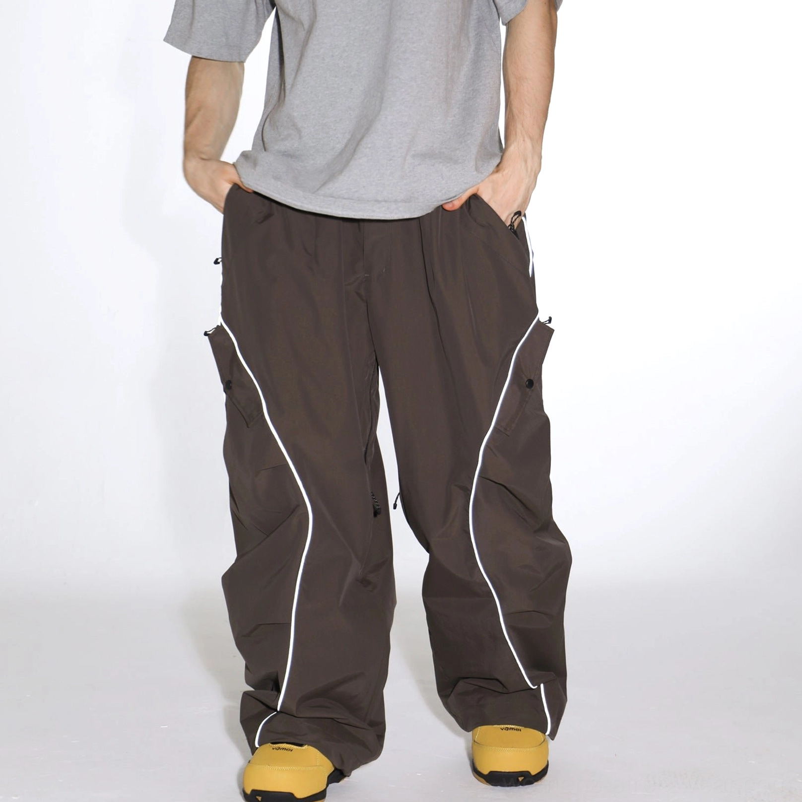 Dark brown reflective piped baggy snowboard cargo pants with loose wide-leg silhouette and zip pockets