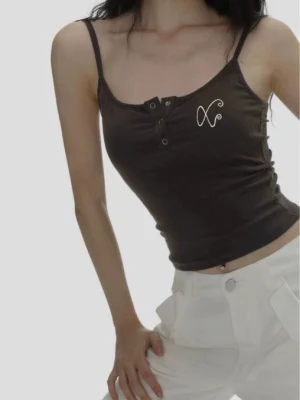 Close up of dark brown fitted cropped camisole with fine ribbed texture, spaghetti straps, Henley buttons, and XO embroidery