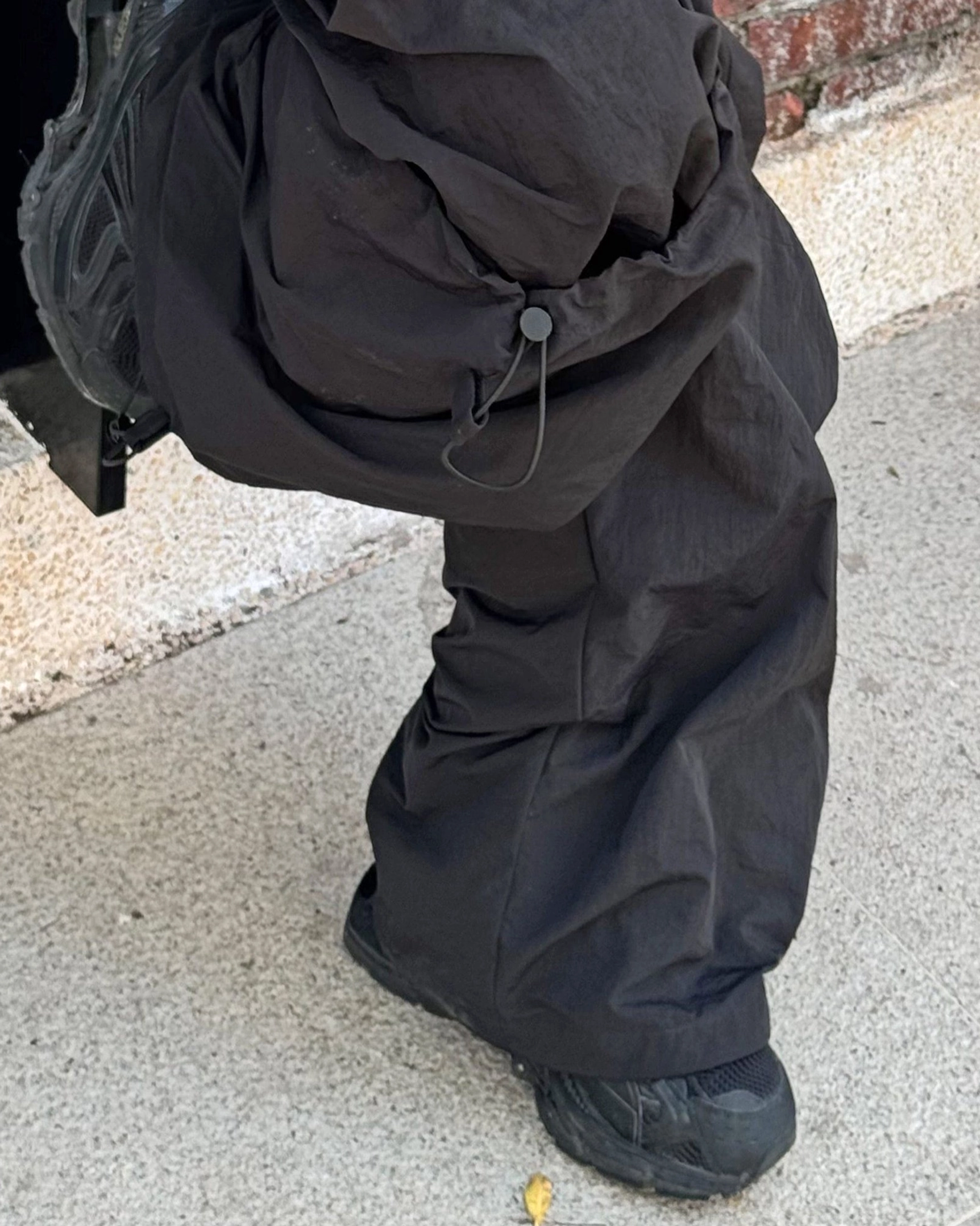 Dark brown technical cargo pants with drawstring waistband wide leg silhouette and adjustable ankle cuffs