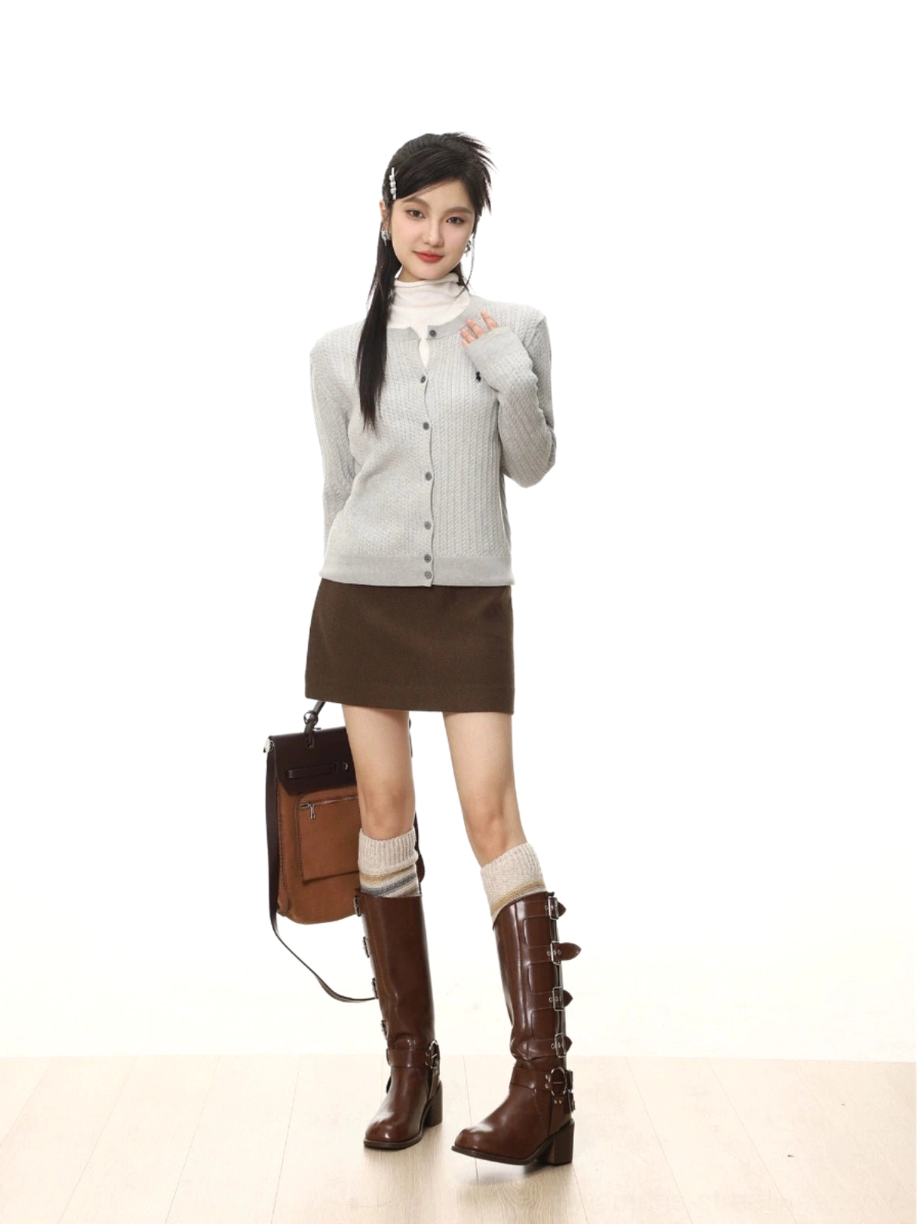 Dark brown high-waisted wool-textured A-line mini skirt styled with a gray cardigan, turtleneck, knee-high boots, and leather tote bag