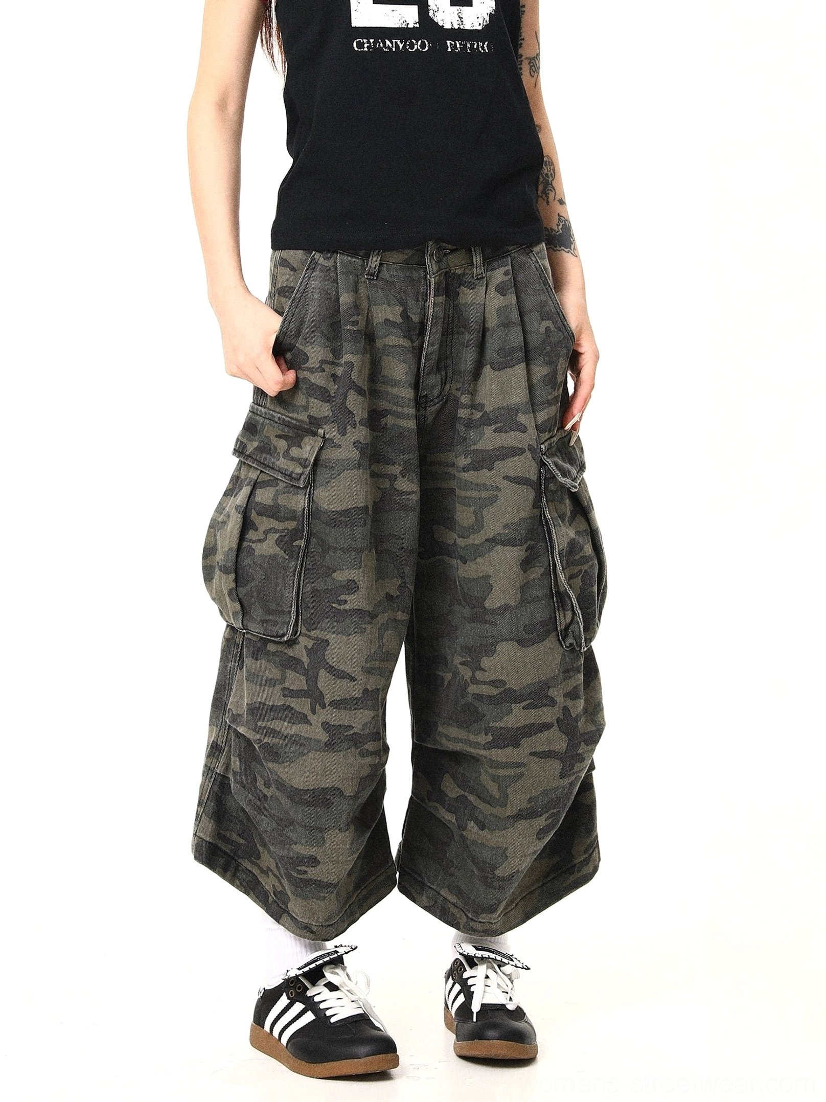 Right side angled view of women’s dark camouflage cargo pants with dual oversized side pockets, pleated high waist, loose wide-leg silhouette, and contemporary utility streetwear appeal