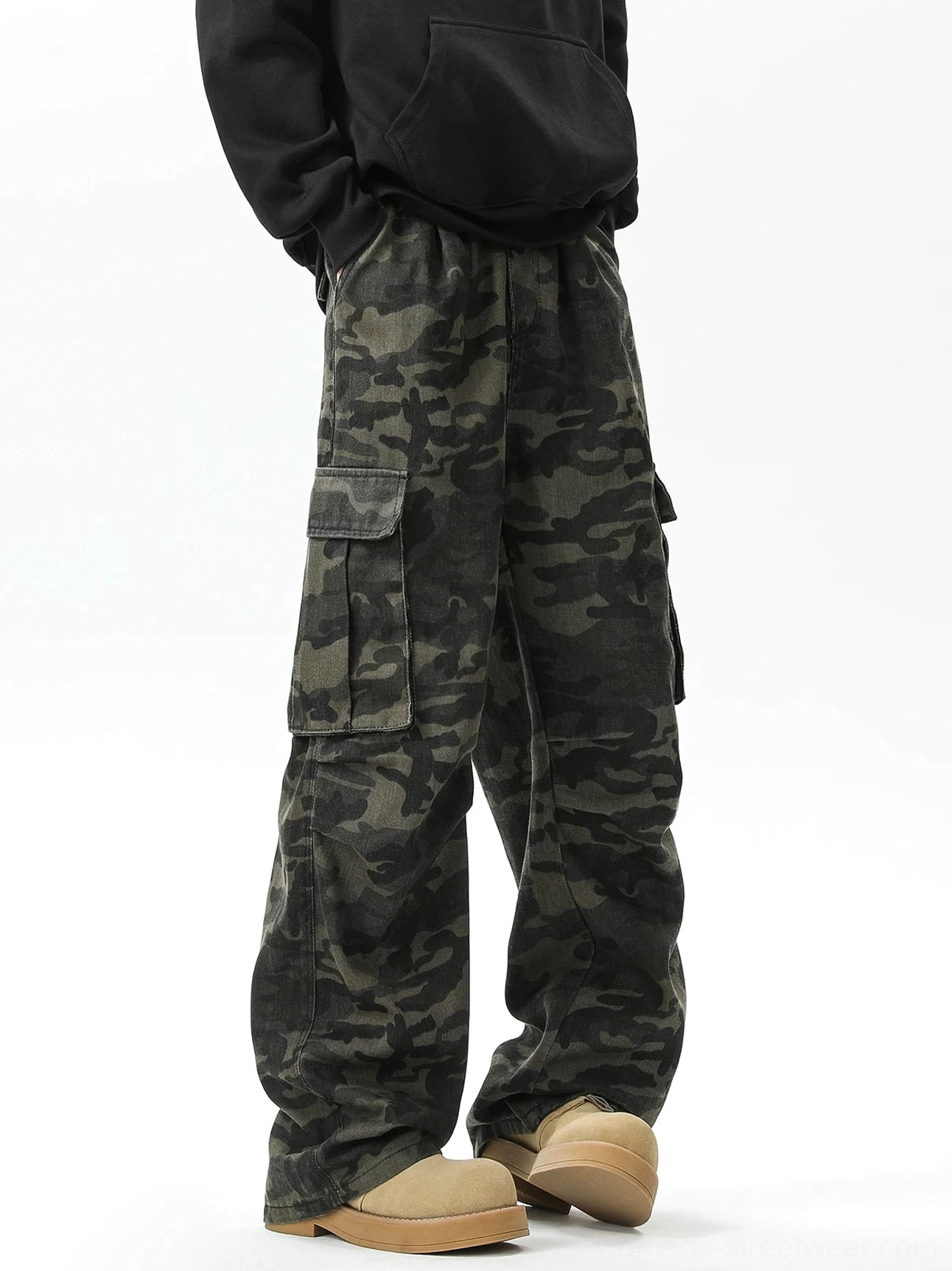 Side view of dark camouflage cargo pants with flap-closed thigh pockets, a loose straight-leg cut, and modern military streetwear styling