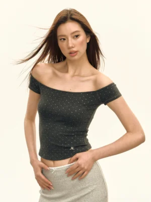 Dark charcoal gray crystal embellished off shoulder ribbed cropped top styled with a light gray low rise skirt in a front three quarter studio view