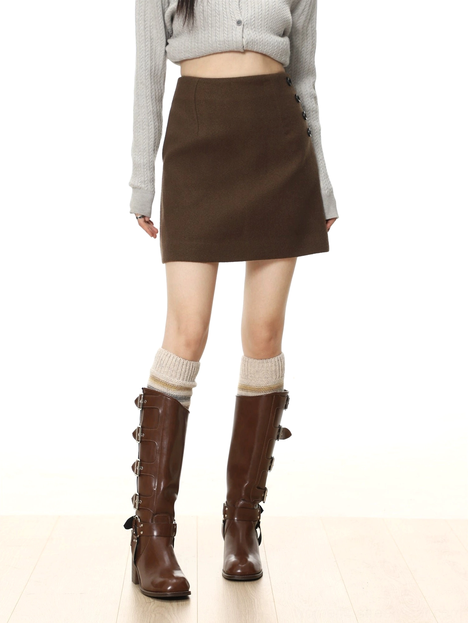 Dark chocolate brown A-line mini skirt with soft woolen texture and decorative black buttons styled with a gray knit top and brown boots