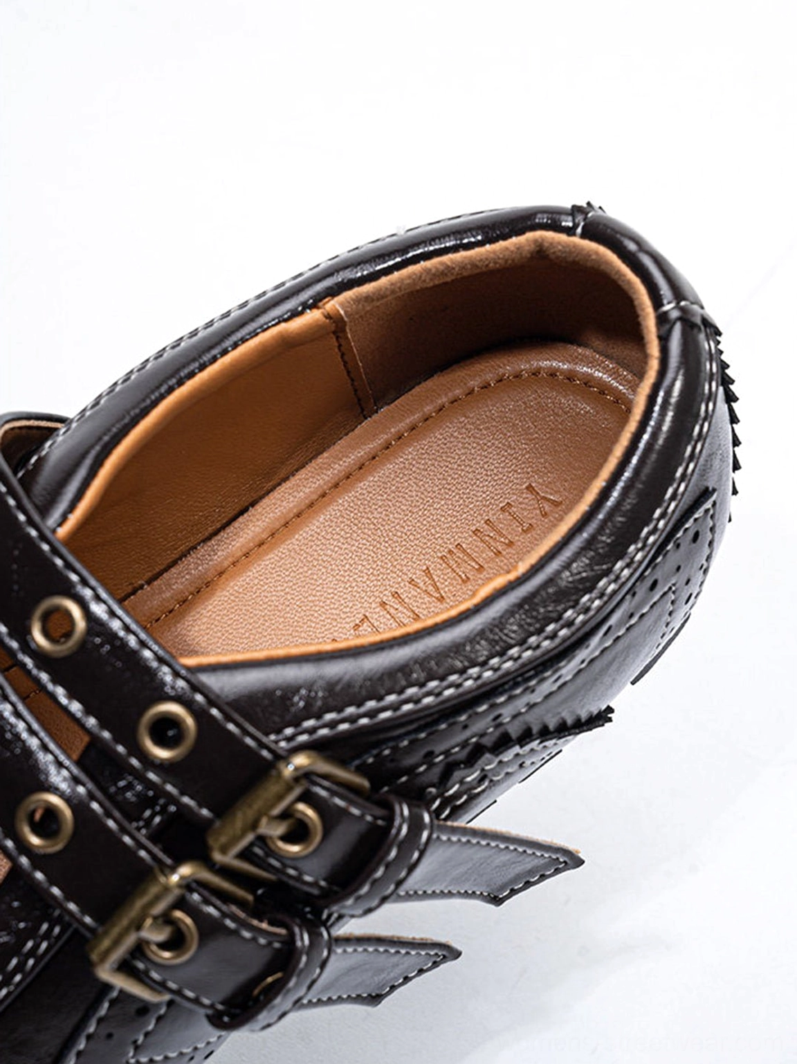 High-angle close-up of dark coffee buckle flat shoe showing the insole metal hardware and precise stitching