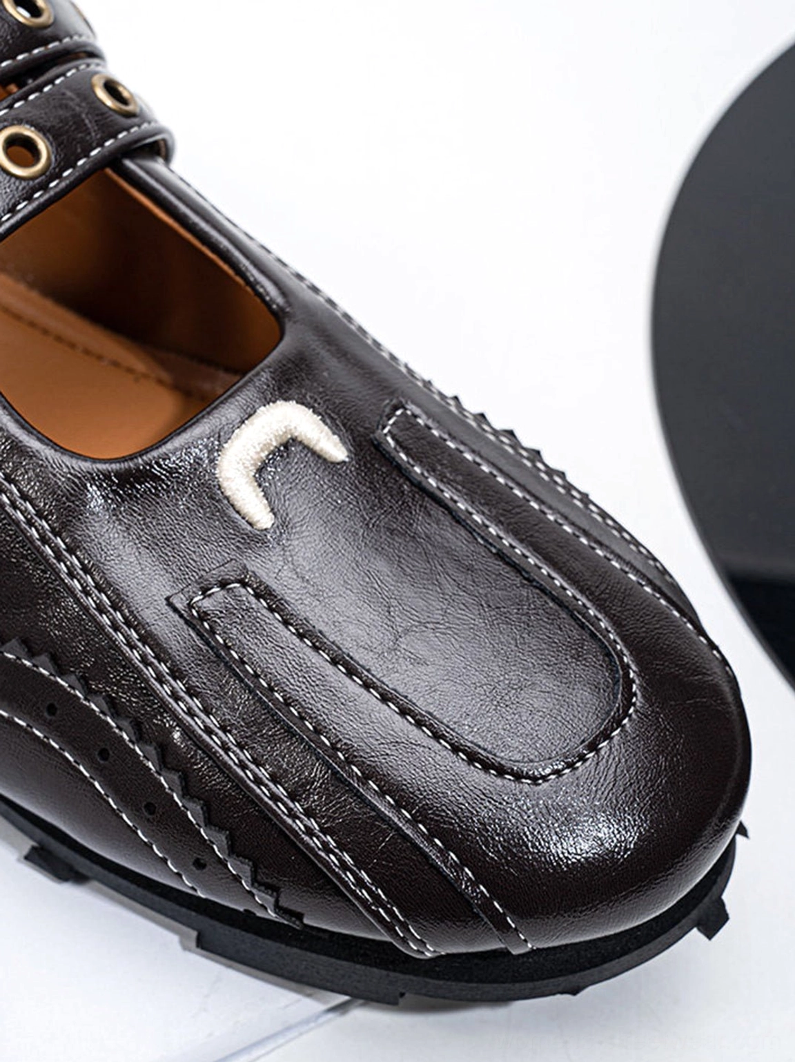 Close-up front view of dark coffee square-toe flats showing glossy finish decorative toe-cap stitching and metal buckle hardware