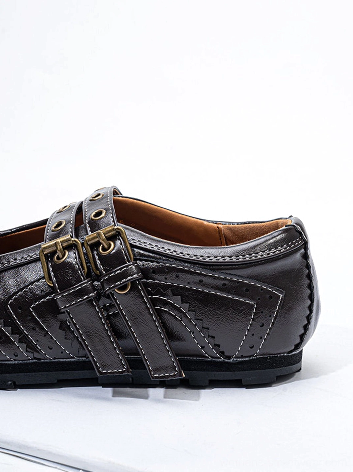 Rear three-quarter view of dark coffee studded double-buckle flats highlighting stitching leather texture and buckle straps
