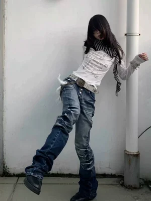 Side angled view of dark cracked wash low-rise scimitar flare jeans with distressed whisker marks and dramatic stacked legs
