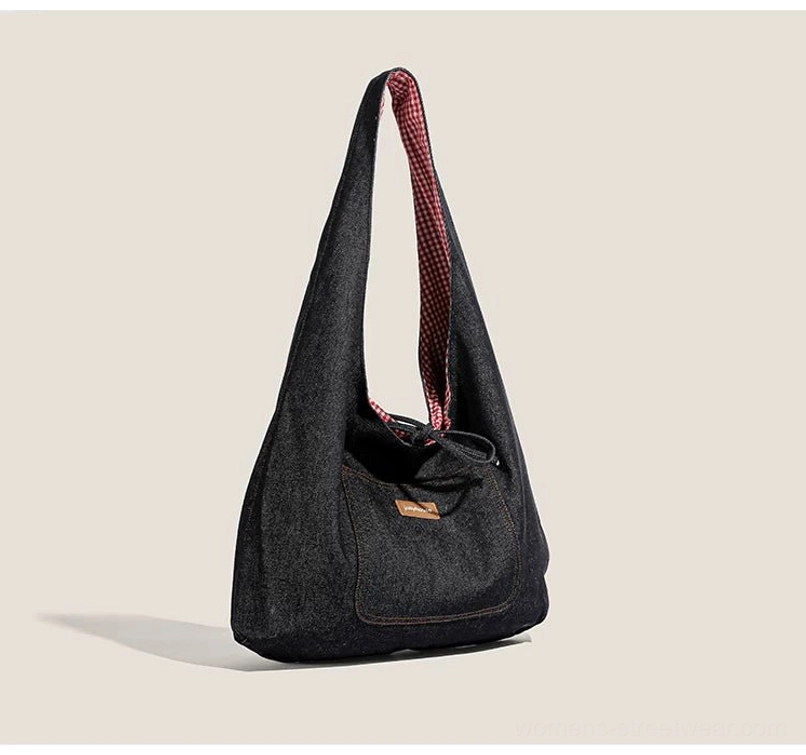 Dark denim drawstring sling tote bag with red gingham lining, front patch pocket, and slouchy hobo shoulder silhouette