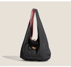Dark denim hobo sling tote side view showing red plaid gingham lining, drawstring closure, and front utility pocket