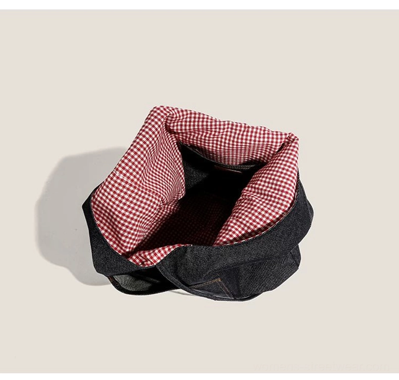 Open dark denim hobo tote viewed from above, displaying spacious red gingham lining and drawstring opening