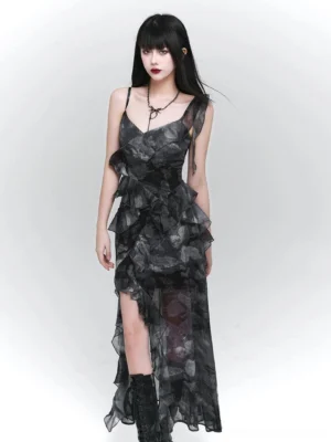 Front view of a dark glamour asymmetrical floral maxi dress with sheer chiffon layers, V-neck spaghetti straps, layered ruffles, high side slit, and platform boots