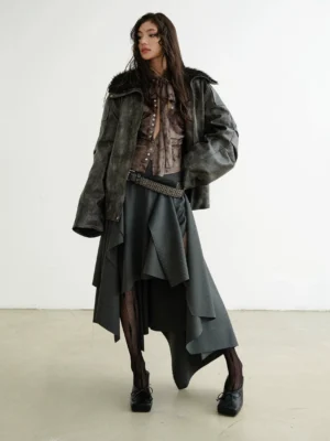 Dark gray asymmetric layered midi skirt with flowing uneven hem styled with a corset top, wide belt, fishnet tights and loafers