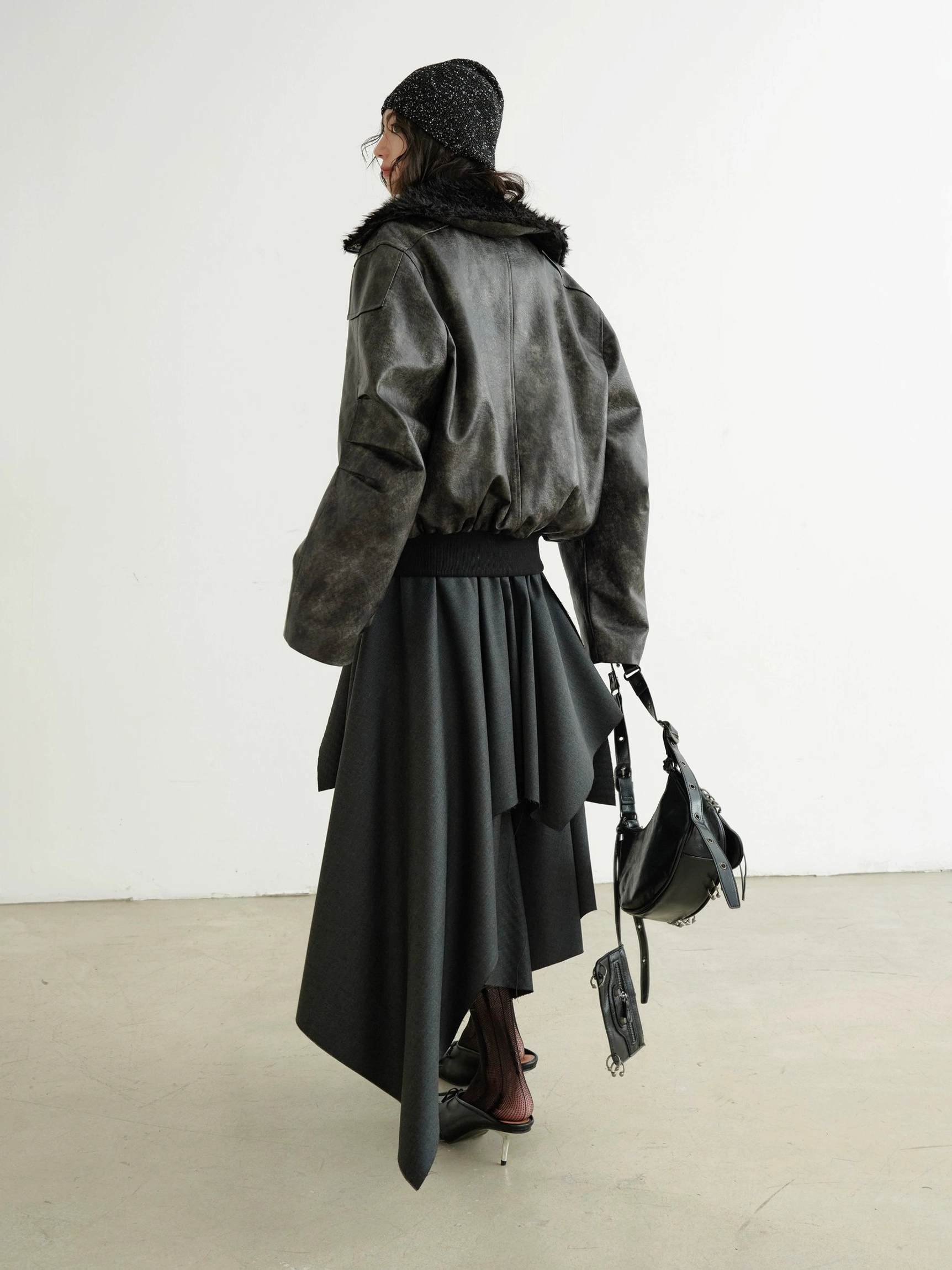 Back view of dark gray asymmetrical layered midi skirt with cascading draped panels styled in a Seoul inspired avant-garde streetwear outfit