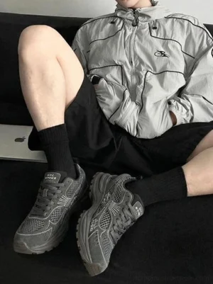 Dark gray chunky mesh runner sneakers worn with black shorts and crew socks in a casual streetwear outfit