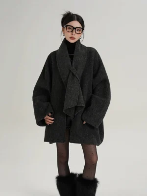 Dark gray oversized wool cocoon jacket with twisted draped scarf collar, relaxed sleeves, melange texture, polka-dot tights, and furry boots