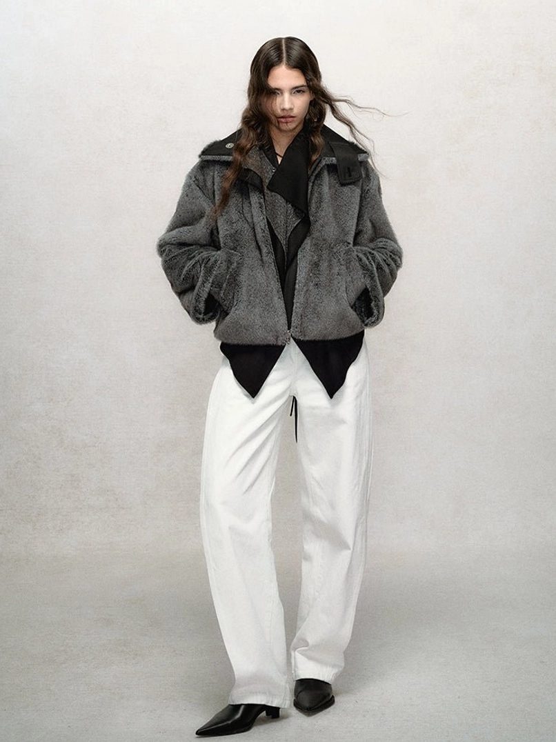 Dark gray cropped faux fur bomber jacket styled with a black top and white wide-leg pants for a modern streetwear outfit
