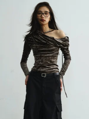 Dark gray crushed velvet asymmetrical off-shoulder long sleeve streetwear top with draped neckline and fitted silhouette shown in a front half-length studio view