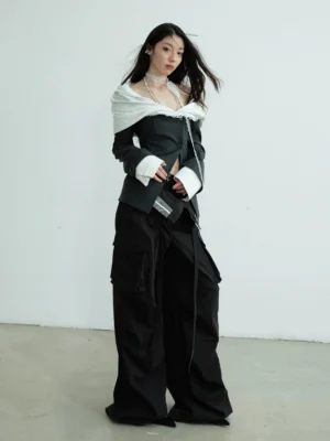 Front view of dark gray deconstructed off-shoulder blazer with white asymmetric collar contrast cuffs and fitted cropped waist