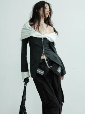 Dark gray deconstructed off-shoulder asymmetric collar blazer styled with wide-leg cargo pants in a minimalist studio side view
