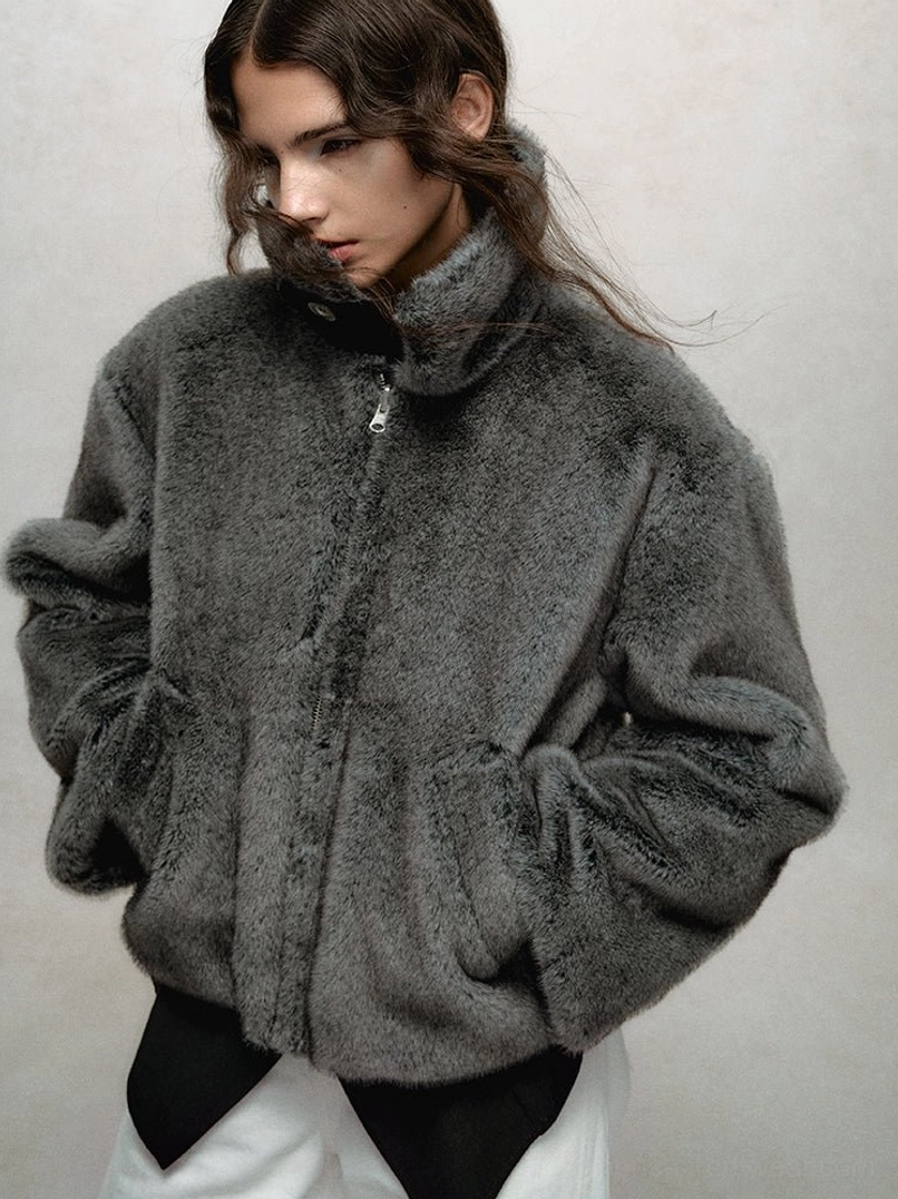 Dark gray faux fur cropped bomber jacket close-up showing the soft plush texture, stand collar, zip closure, and relaxed sleeves