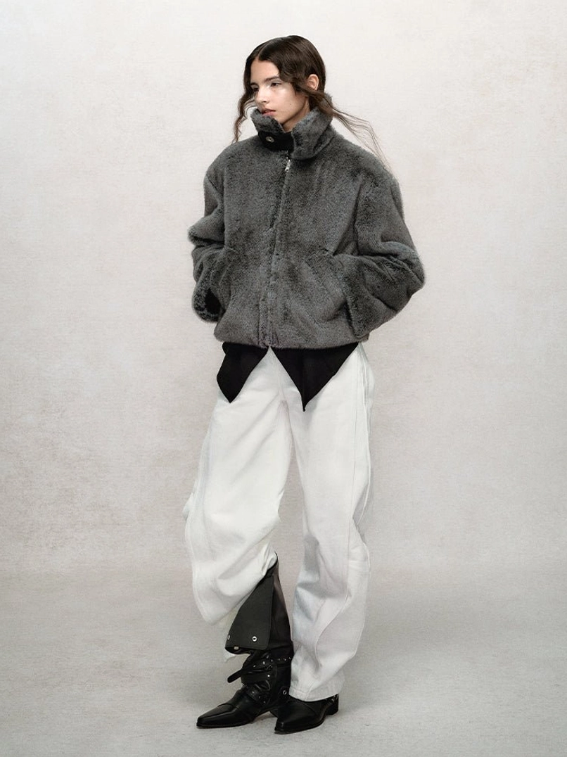 Dark gray faux fur winter bomber jacket shown from a side-front angle with drop shoulders, cropped length, and fuzzy plush fabric