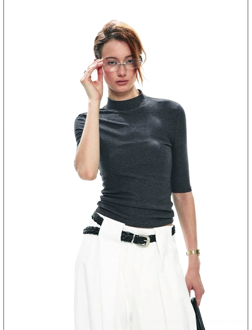 Dark gray fitted mock neck half-sleeve streetwear top styled with white wide-leg trousers and leather belt