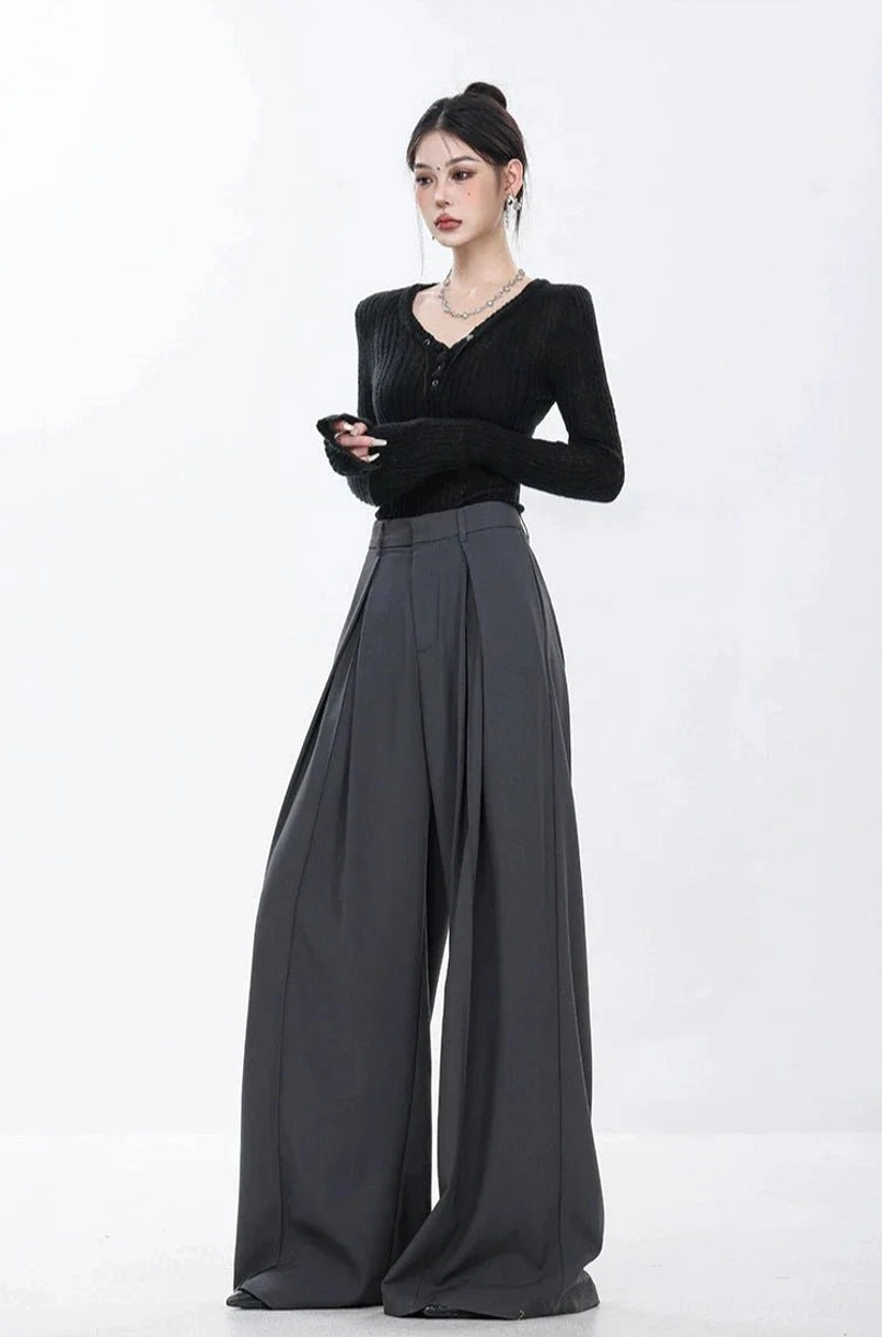 Three-quarter front styling of dark gray full-length pleated wide-leg trousers with a fitted black top