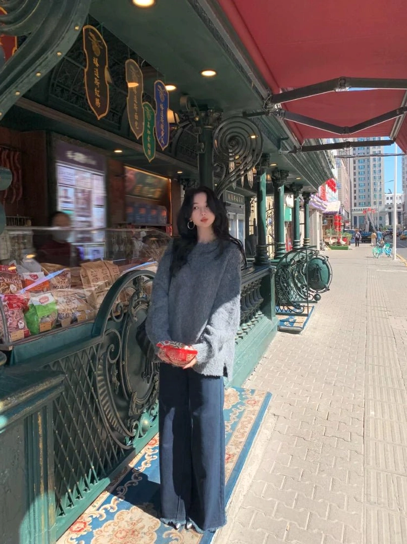 Dark gray fuzzy knit sweater with relaxed long-sleeve fit styled with navy wide-leg pants outside a vintage European street shop