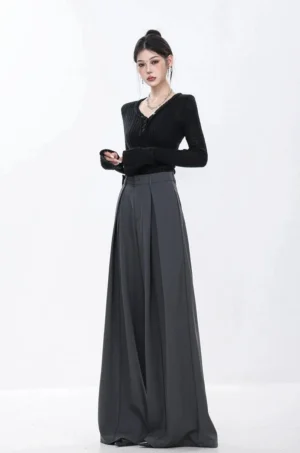 Three-quarter front view of high-rise dark gray tailored wide-leg trousers with deep pleats and black knit top