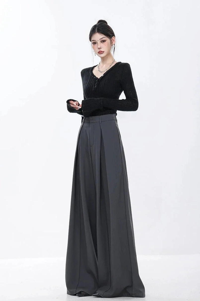 Three-quarter front view of high-rise dark gray tailored wide-leg trousers with deep pleats and black knit top