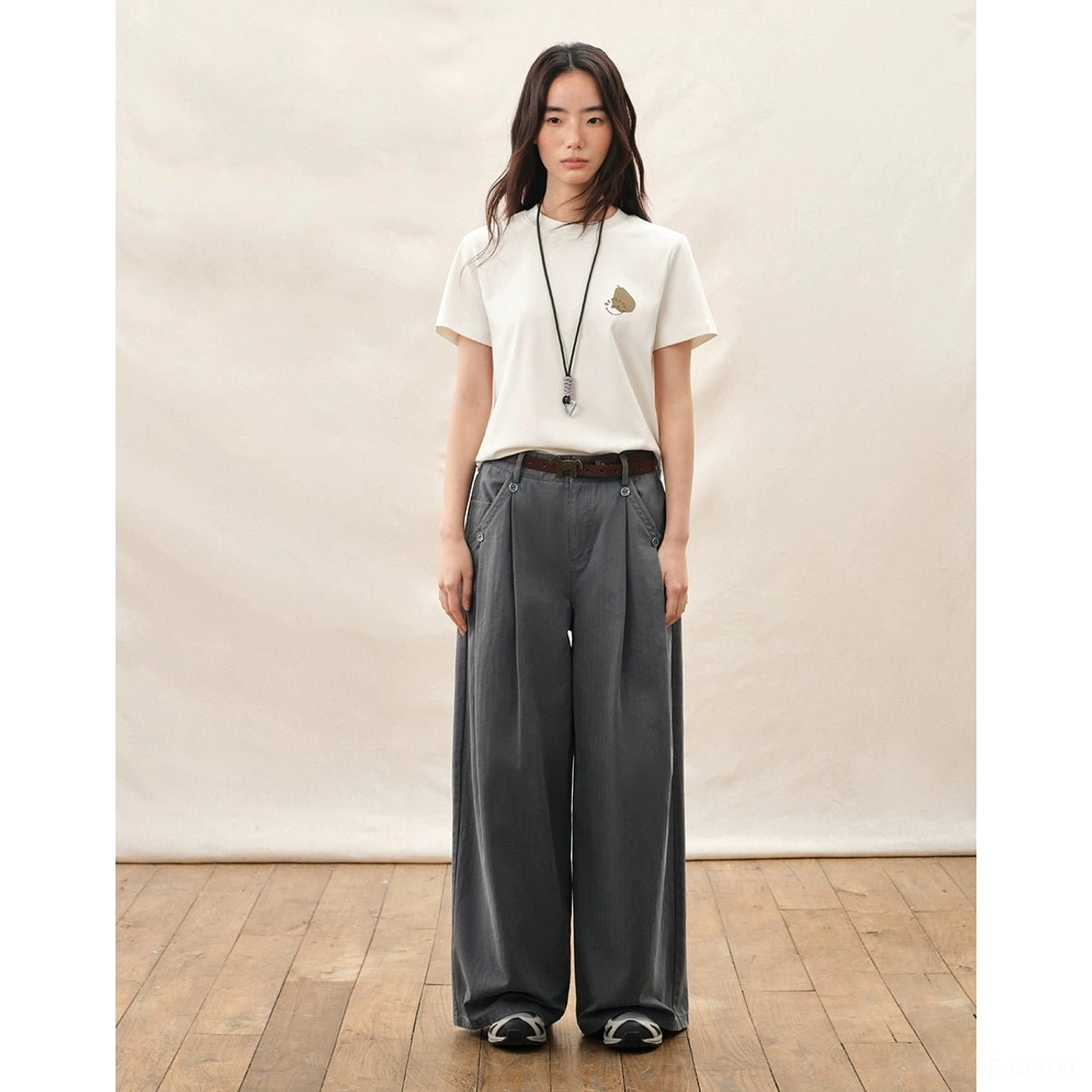 Dark gray high waisted pleated wide leg streetwear pants styled with a white tee leather belt and casual shoes