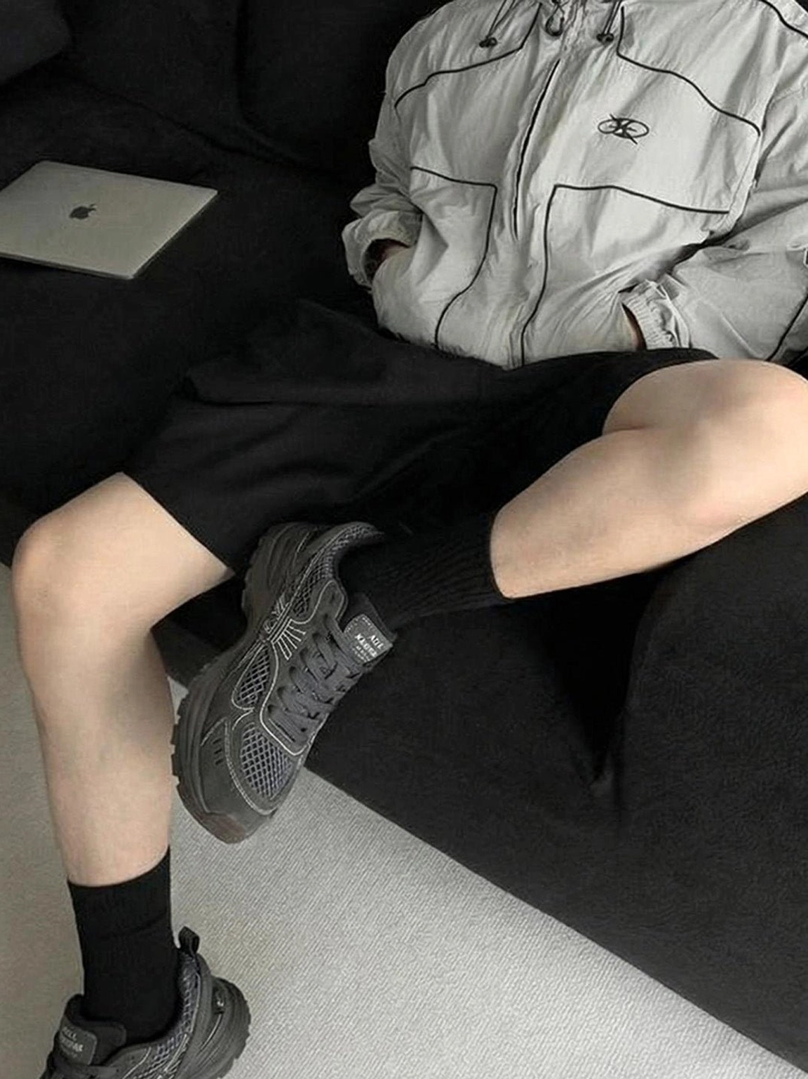 Dark gray layered runner sneakers styled on feet with relaxed Seoul-inspired streetwear and black socks