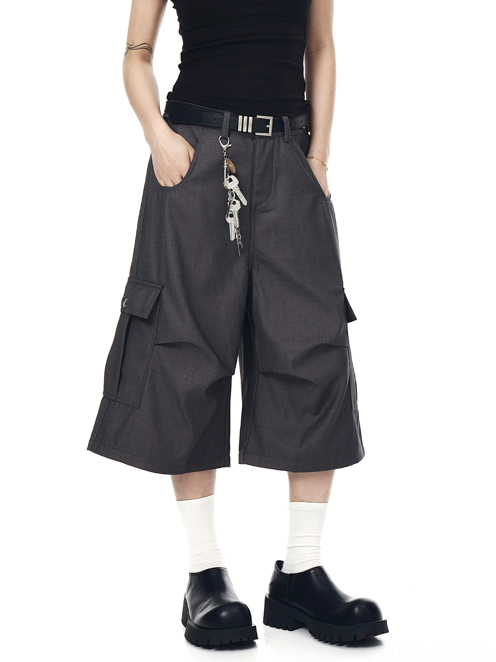 Dark gray oversized cargo culotte shorts shown with hands in pockets, wide-leg silhouette, and functional side cargo pockets