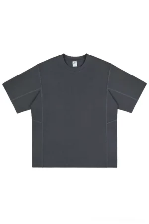 Dark gray oversized cotton patchwork-inspired streetwear T-shirt with crew neck, dropped shoulders, tonal seam stitching, and relaxed unisex fit shown from the front