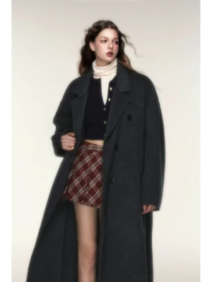 Dark charcoal gray oversized double-breasted merino wool coat styled with a cream turtleneck, dark cardigan, and red plaid mini skirt in a contemporary Korean streetwear outfit