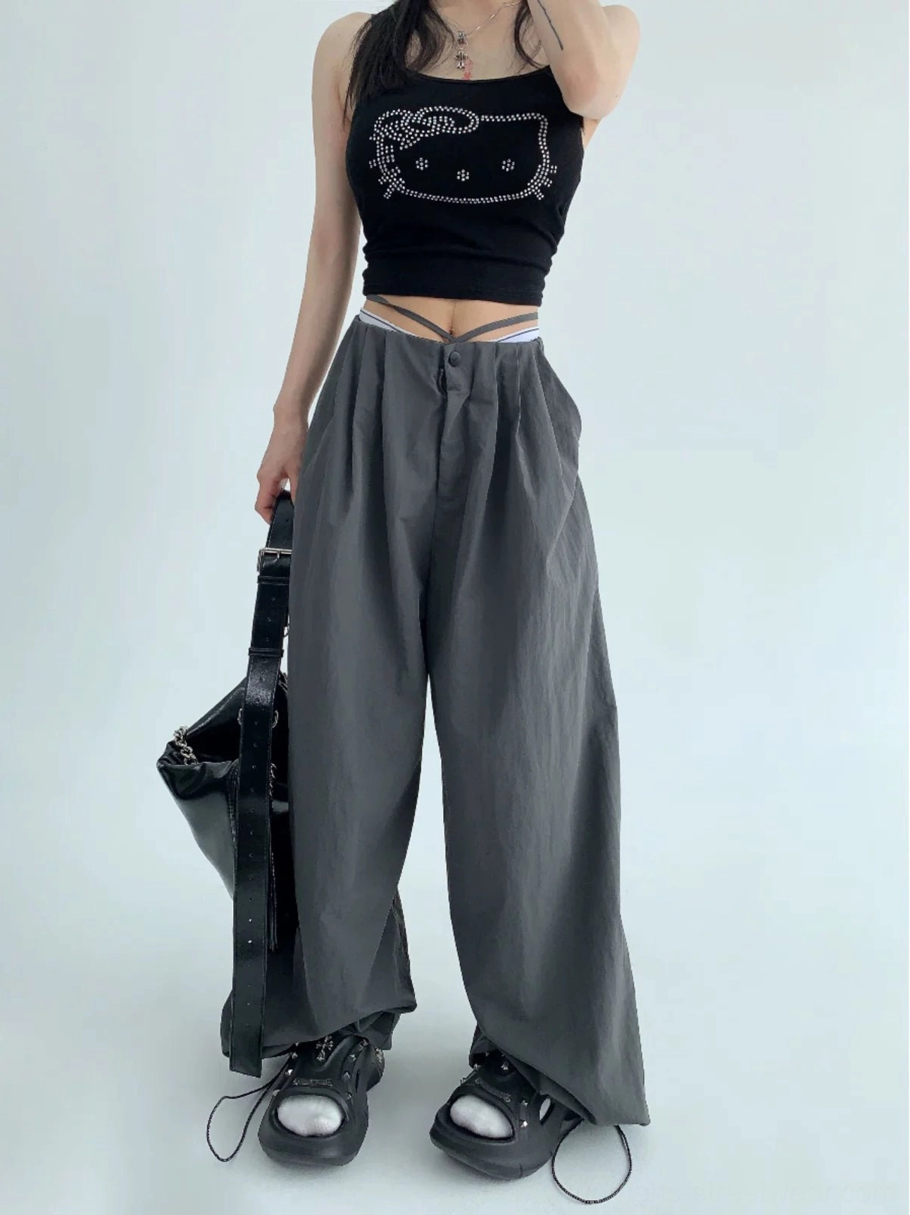 Dark gray oversized parachute pants styled with a black graphic cropped camisole and large leather tote bag