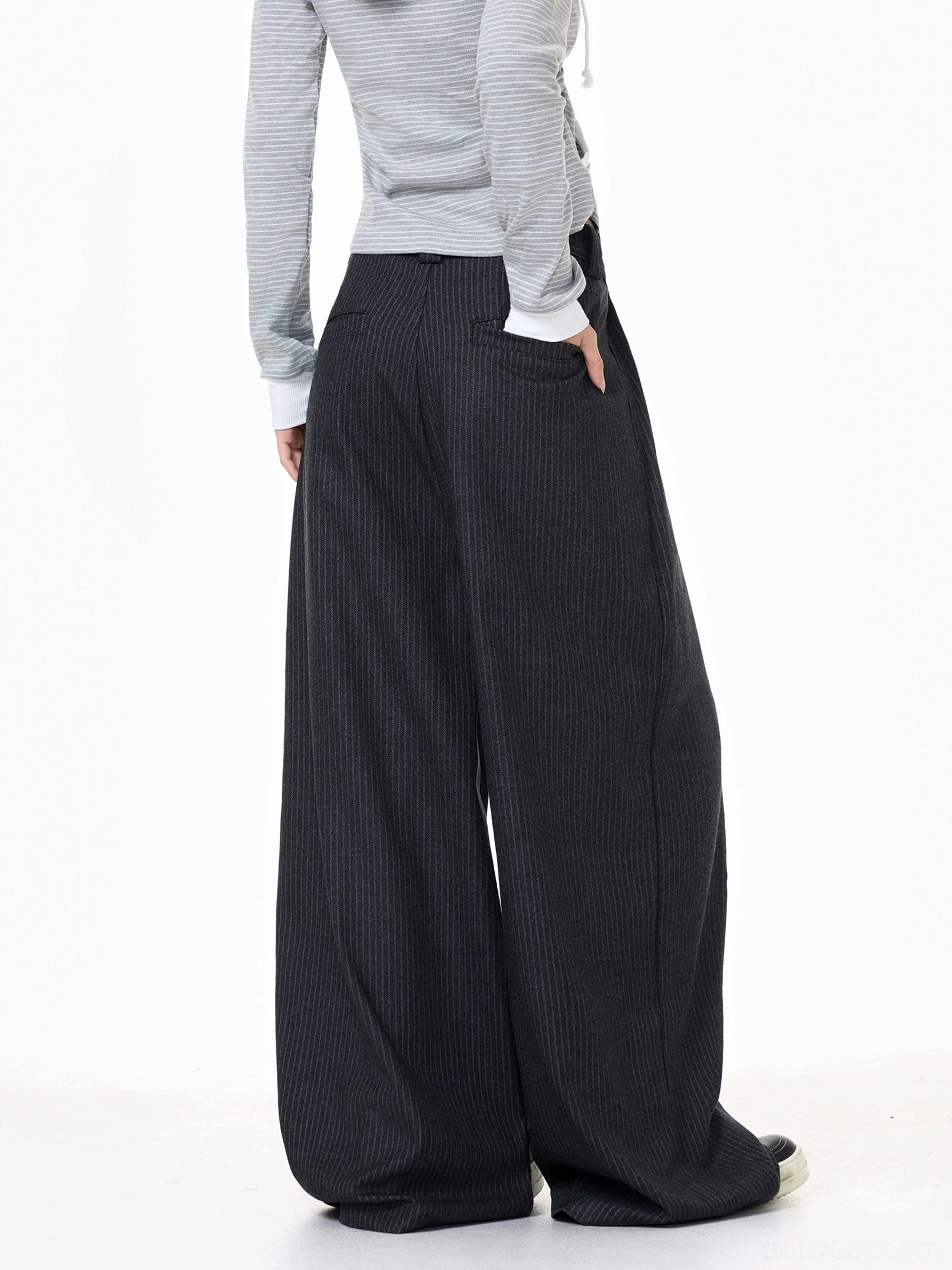 Back side view of oversized dark gray pinstripe trousers showing the clean waistband, rear pocket, and flowing wide-leg drape