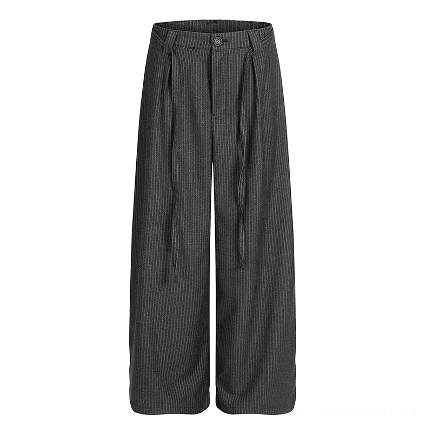 Flat lay of dark gray pinstripe wide-leg trousers showing the full silhouette, front pleats, button closure, pockets, and long waist ties
