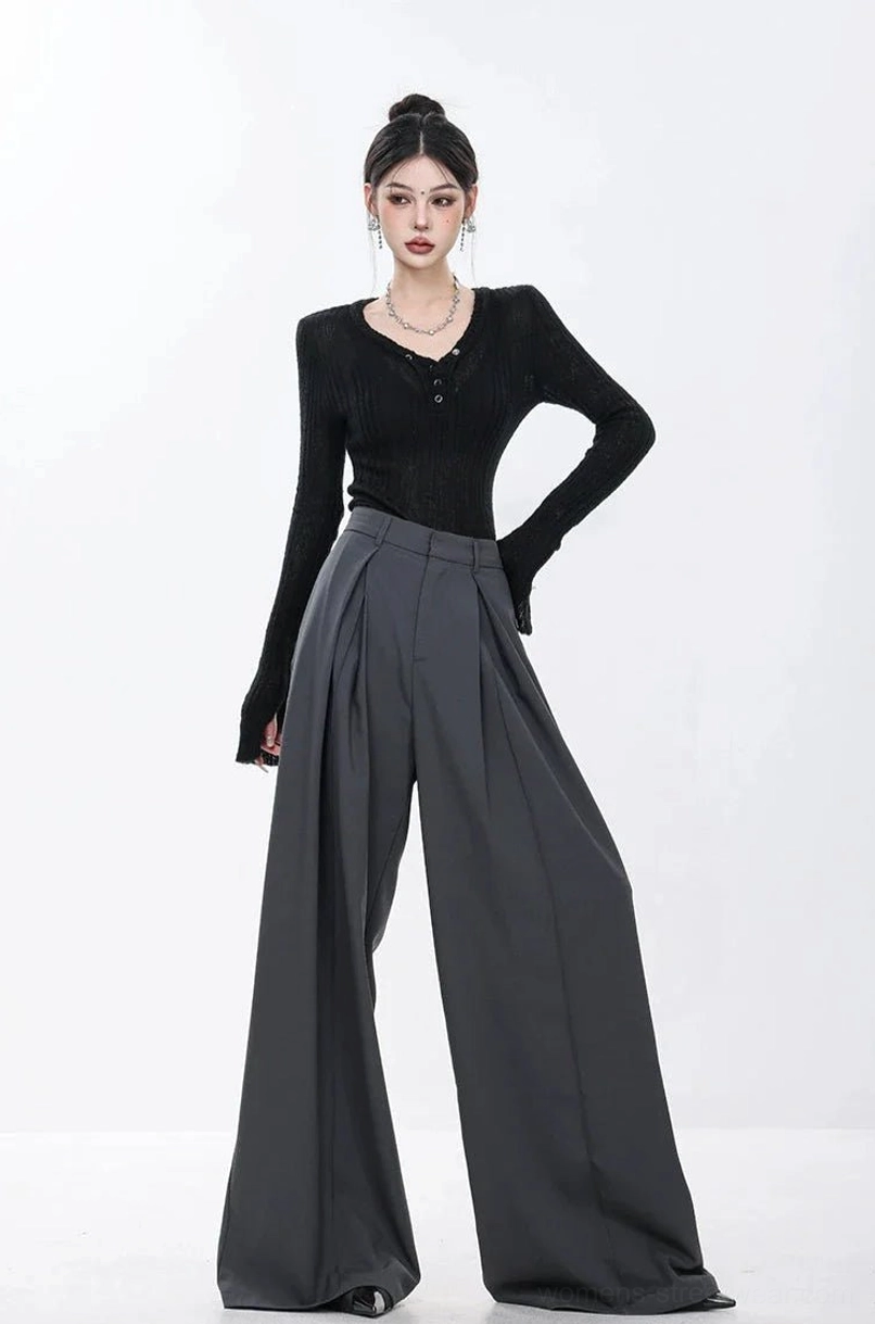 Side three-quarter view of dark gray pleated streetwear pants with a fluid full-length wide-leg cut