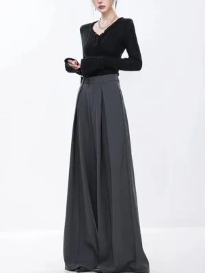 Front full-body view of dark gray pleated wide-leg streetwear trousers styled with a black long-sleeve knit top