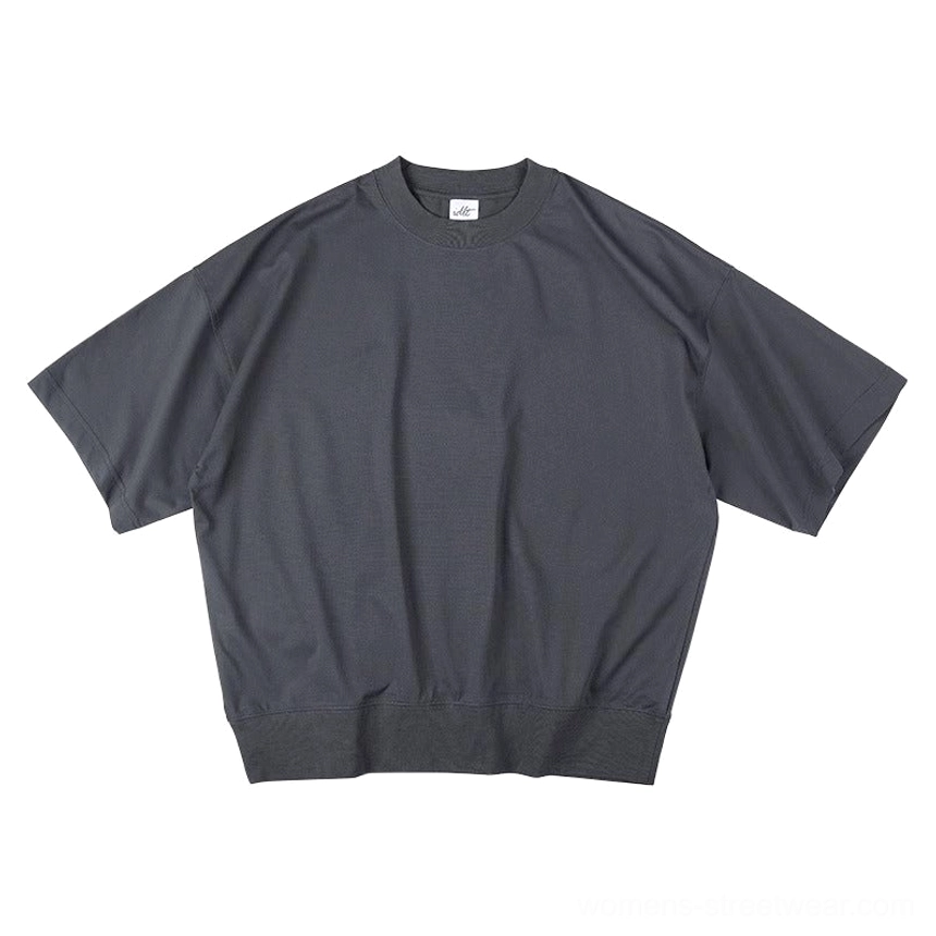 Side view of dark gray relaxed fit sweater tee showing dropped shoulder construction and ribbed bottom hem