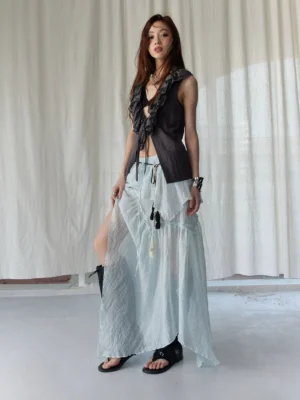 Three quarter view of dark gray ruffle waistcoat and mint green sheer layered skirt with tassel waist details in Korean streetwear style