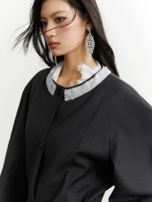 Close-up of the silver white ruffle halo neckline on dark gray pleated swing shirt jacket