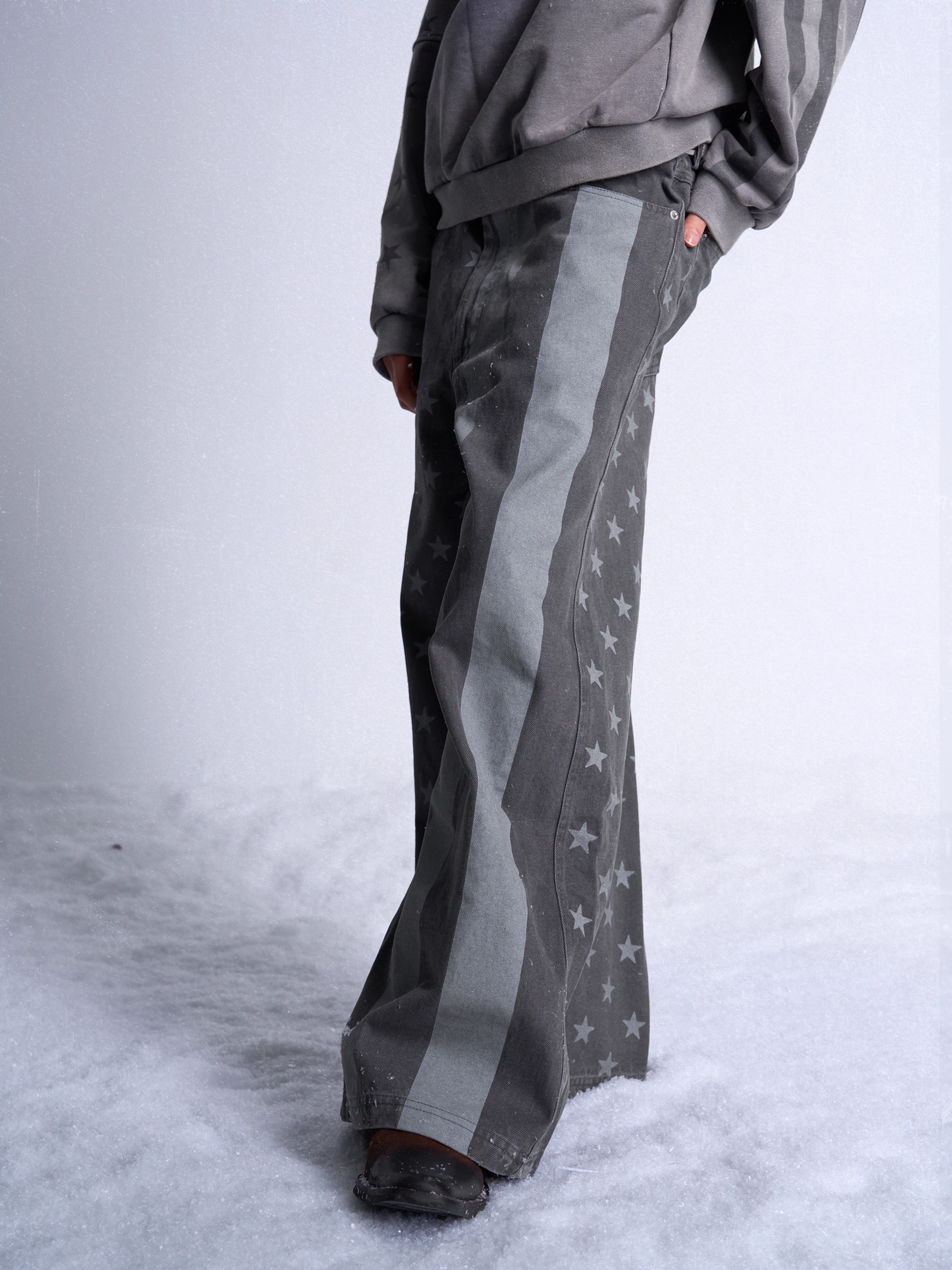 Side rear view of dark gray stars and stripes denim jeans with a relaxed draped wide leg silhouette